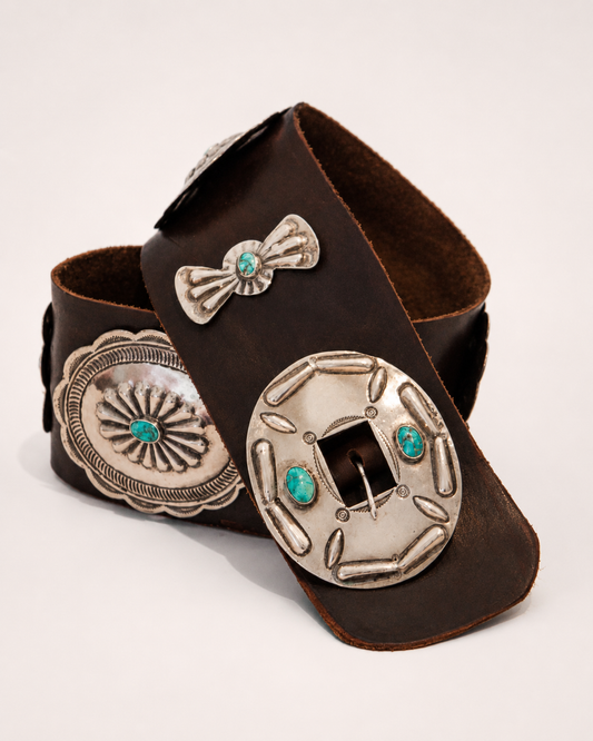 Brown leather belt with silver concho and turquoise stone design on a light gray background