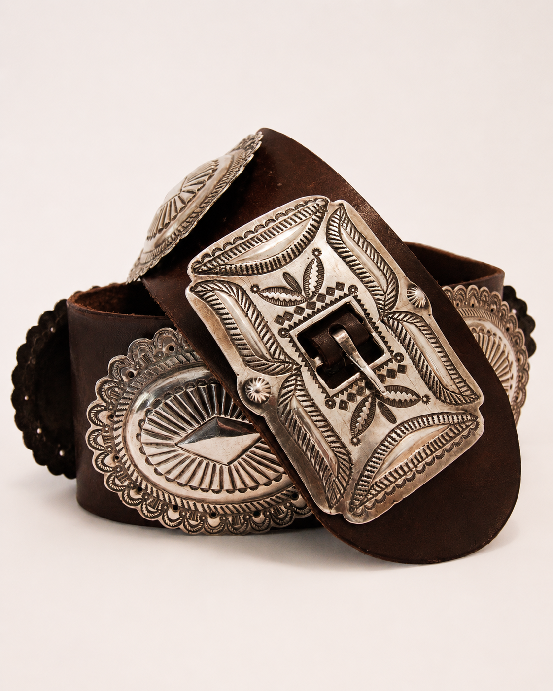 Brown leather belt with silver concho-style buckles on a white background