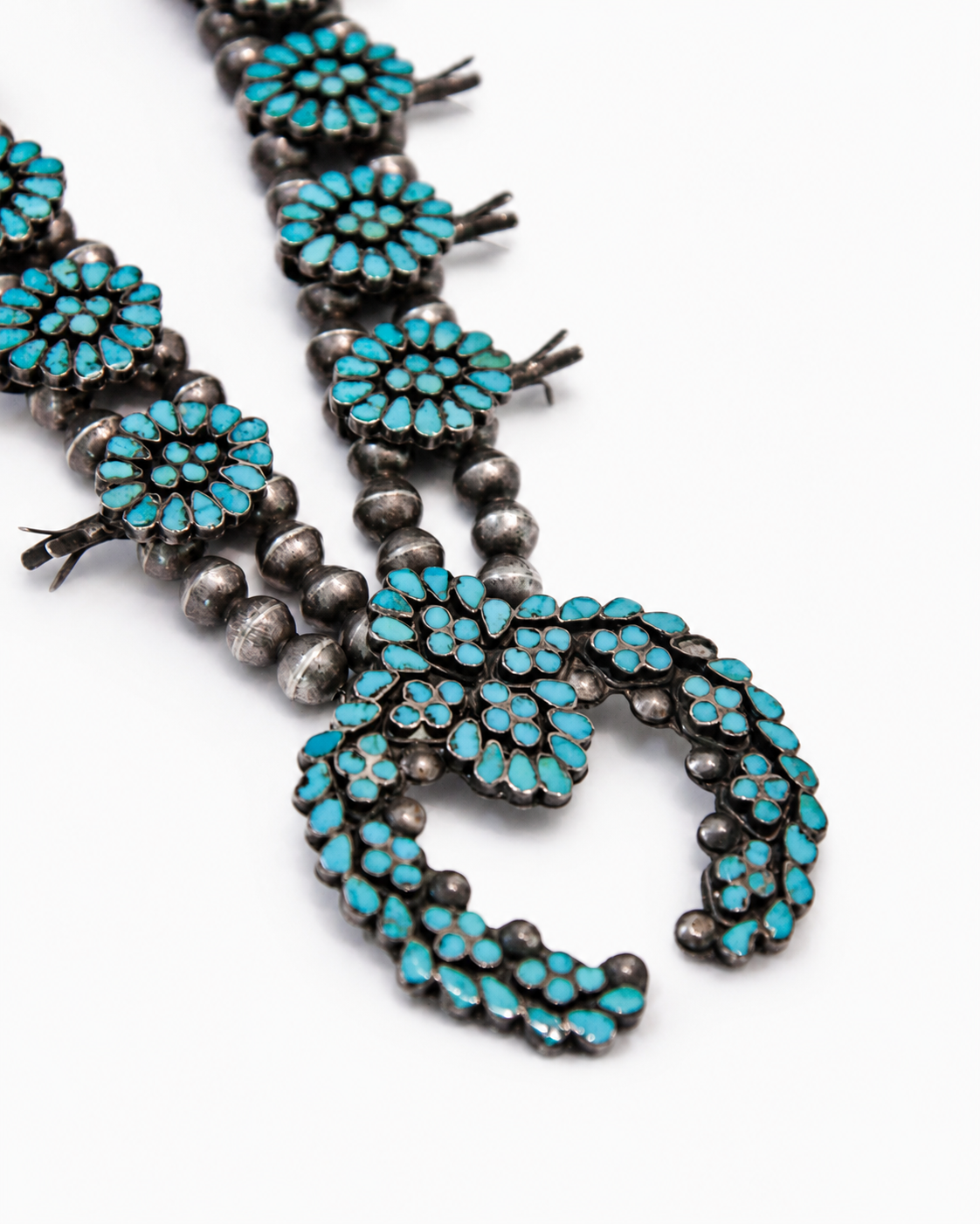 Turquoise and silver beaded necklace on a white background