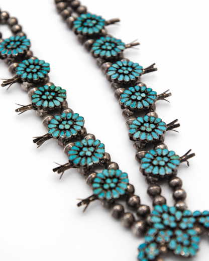 Turquoise beaded necklace with silver accents on a white background