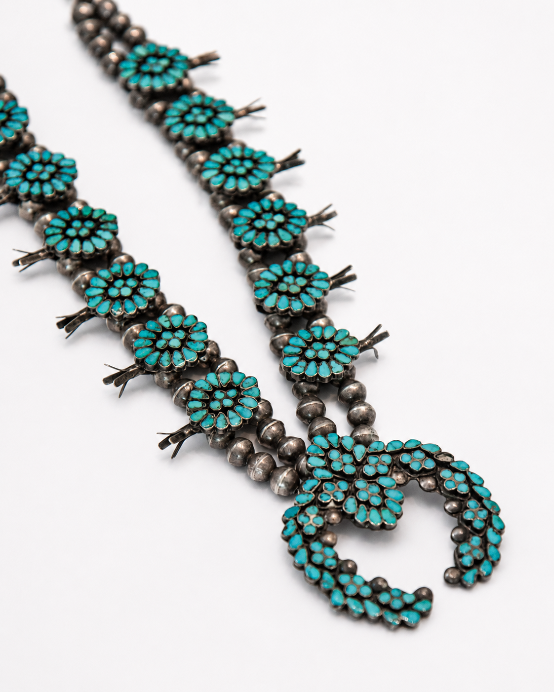 Turquoise beaded necklace with silver accents on a white background