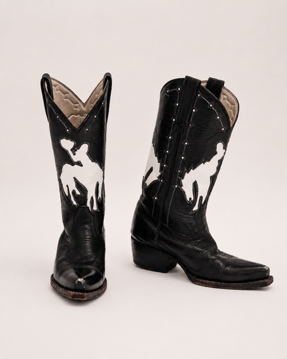 Black cowboy boots with white bucking bronco design on a light gray background