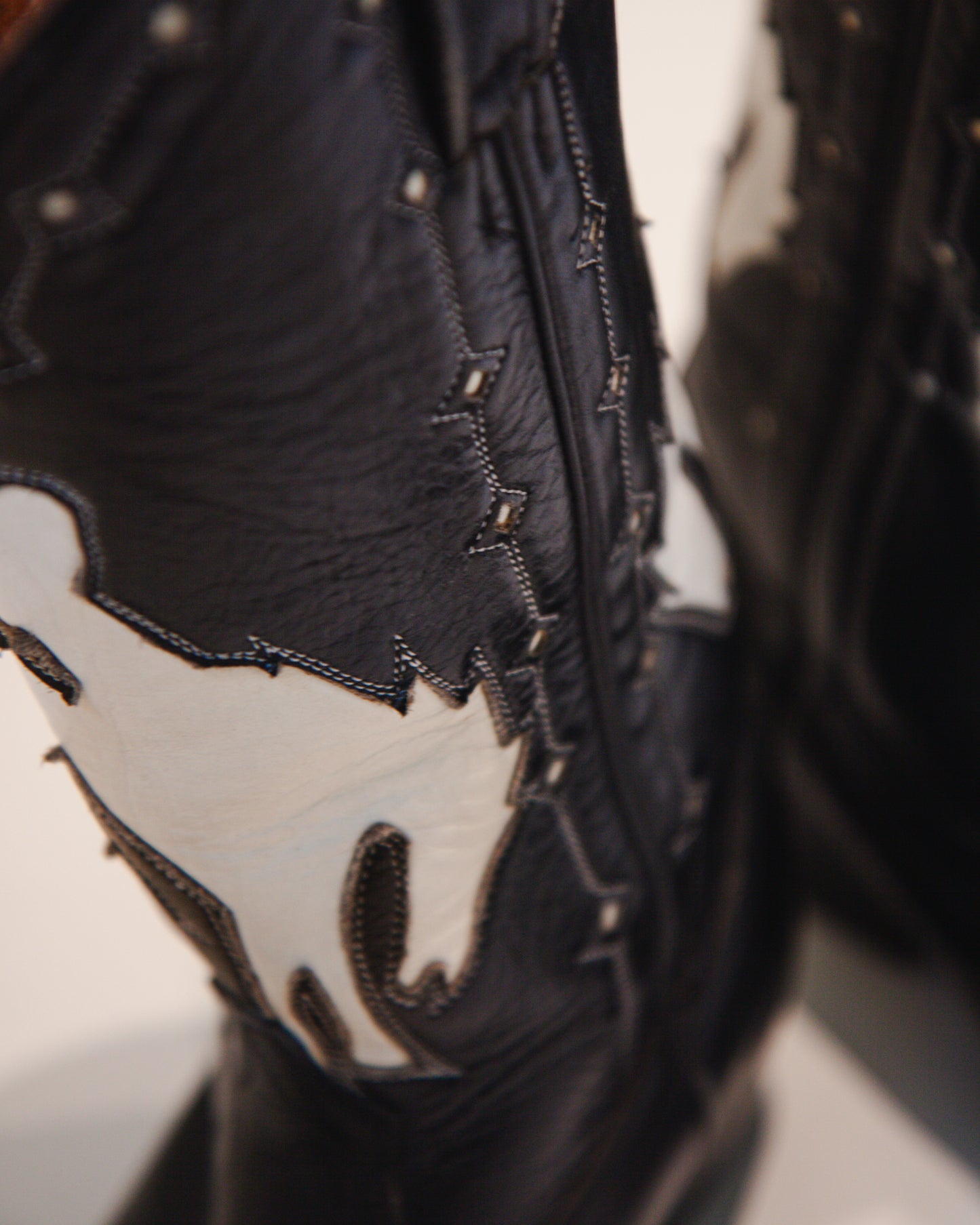 Close-up of a black leather boot with white accents on a blurred background