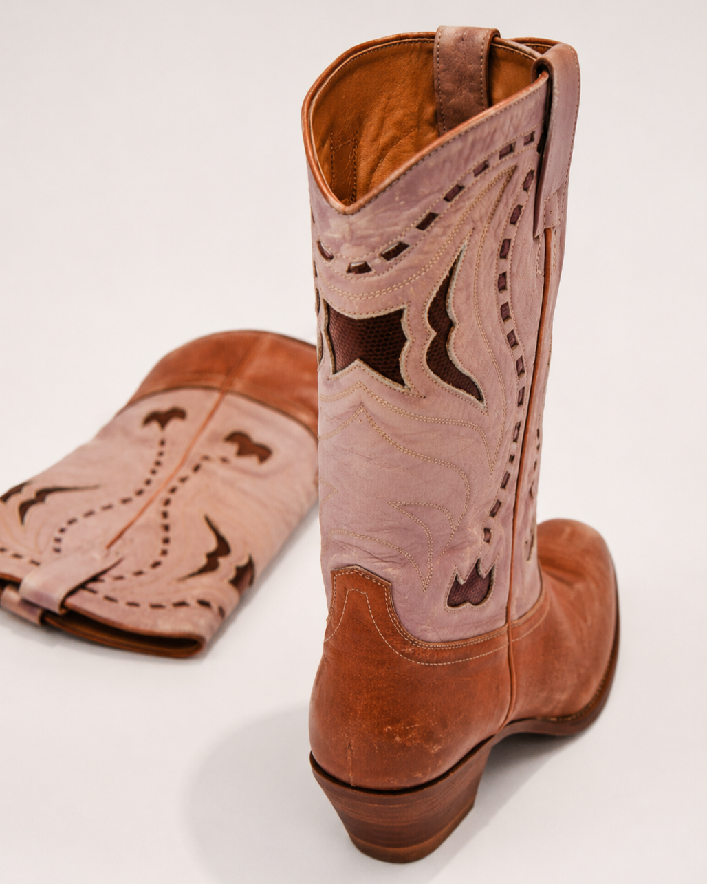 Brown cowboy boot with intricate stitching on a white background