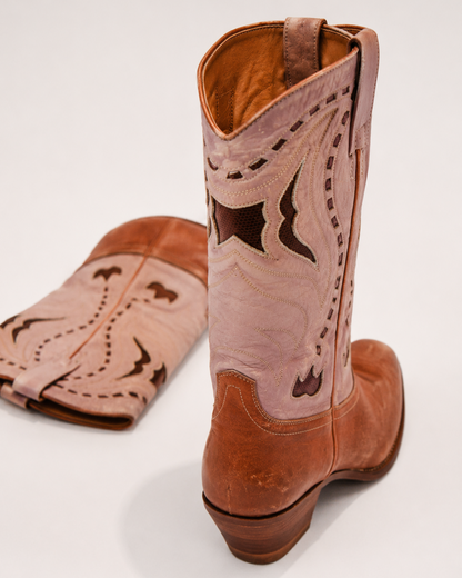 Brown cowboy boot with intricate stitching on a white background