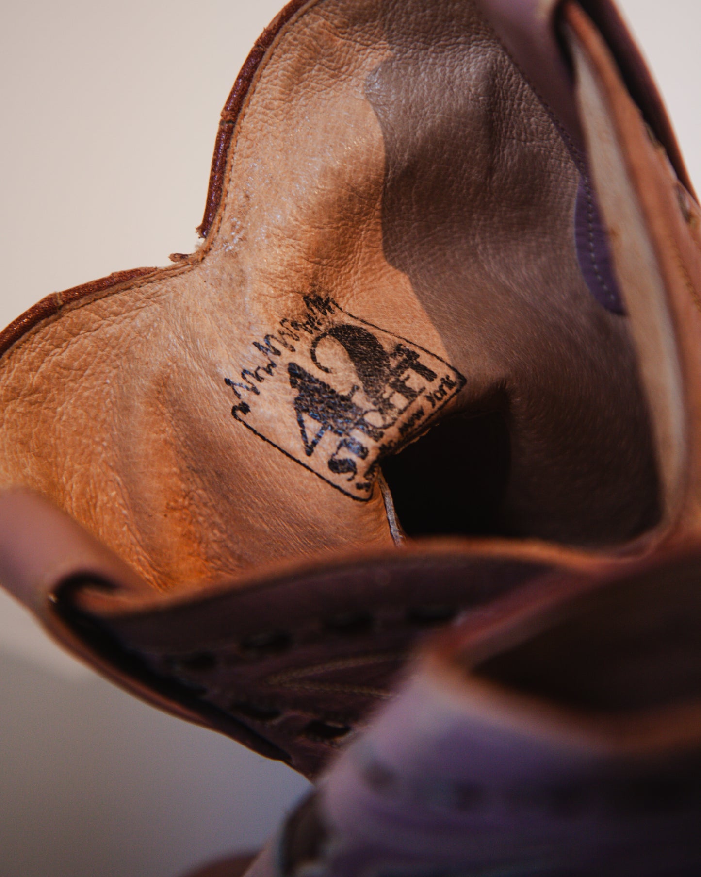 Close-up of a brown leather shoe with a brand logo on a light background