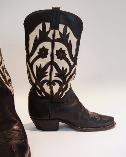 Black cowboy boot with white floral patterns on a white background