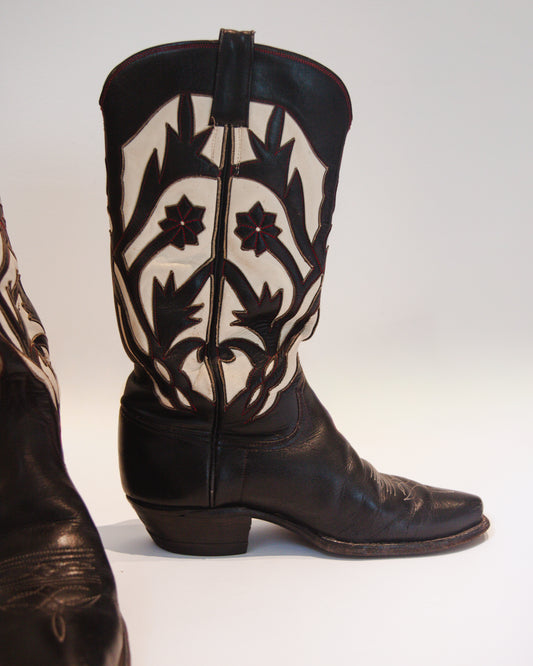 Black cowboy boot with white floral patterns on a white background