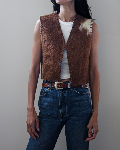 Woman in vest and denim jeans on a white background.