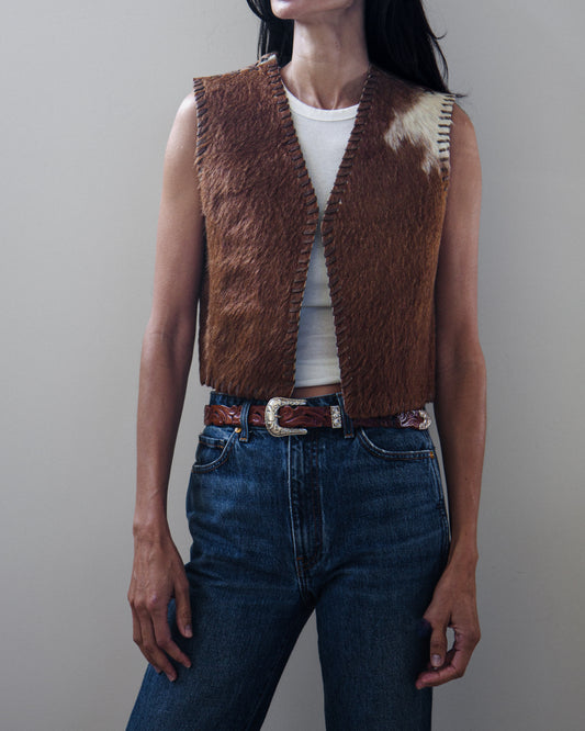 Woman in vest and denim jeans on a white background.