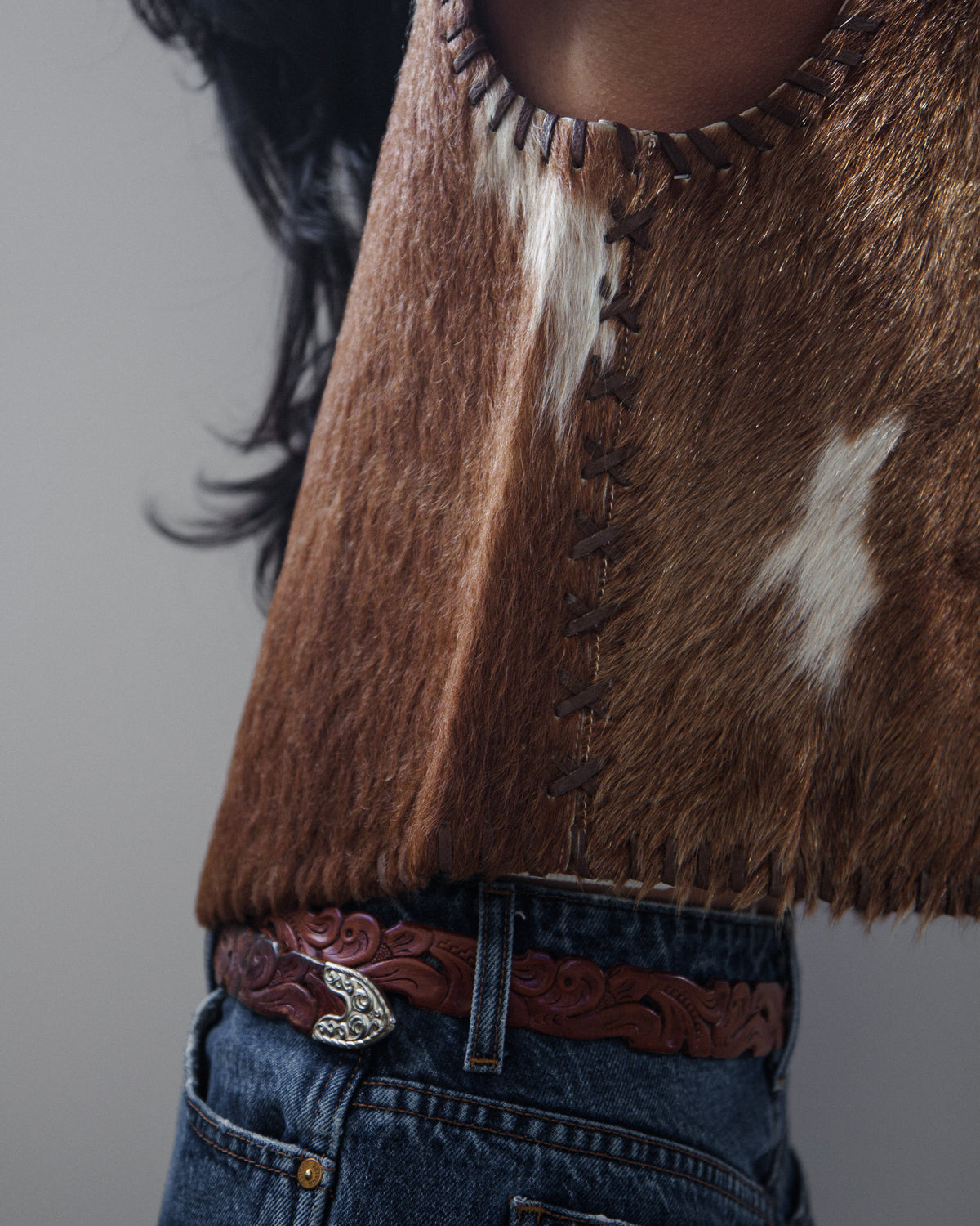 Side view of woman in vest and denim jeans on a white background.