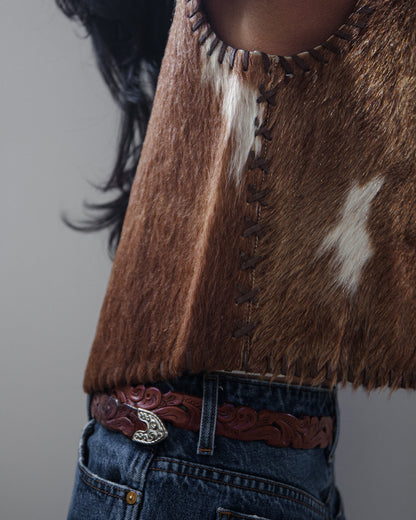 Side view of woman in vest and denim jeans on a white background.