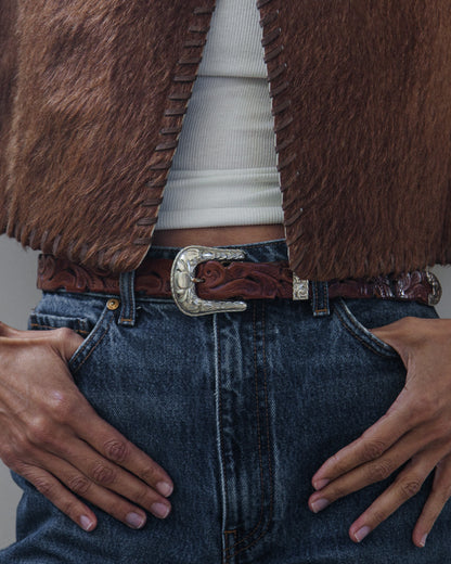 Detailed image of Woman in vest and denim jeans on a white background.