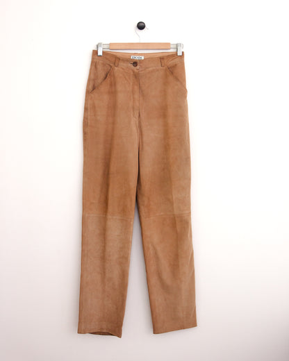 High-waisted tan corduroy trousers, a blue patterned button-up shirt, and brown suede shoes, standing against a plain off-white wall.