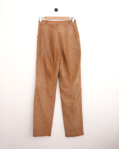 High-waisted tan corduroy trousers, a blue patterned button-up shirt, and brown suede shoes, standing against a plain off-white wall.