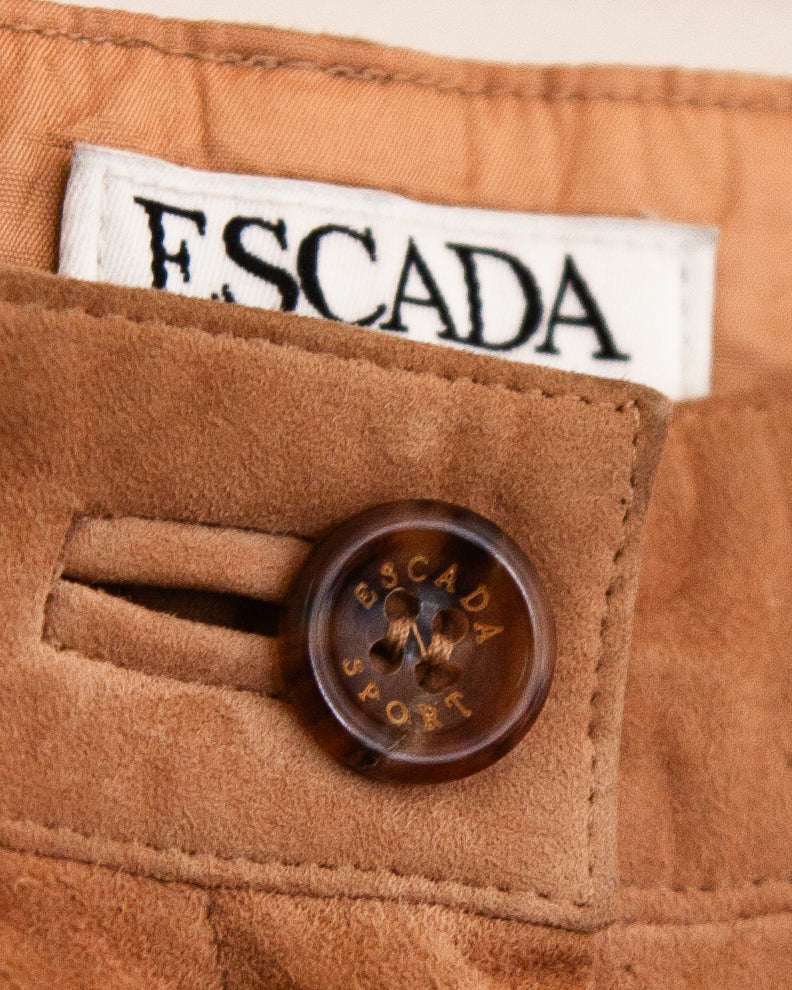 A close-up of a brown suede or suede-like fabric with Escada Sport tag and close up of button.