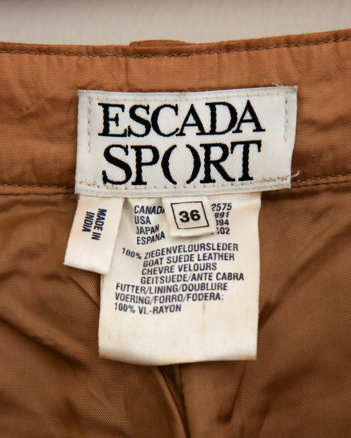A close-up of a brown suede or suede-like fabric with Escada Sport tag.