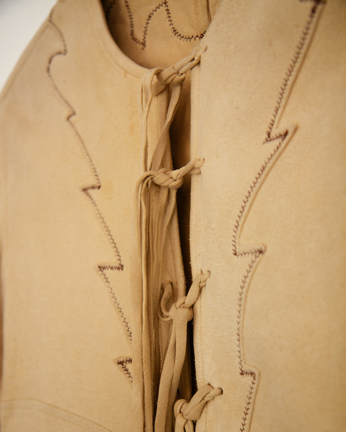 A light beige long-sleeve blouse with decorative tie-front laces detailing.