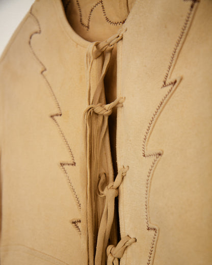 A light beige long-sleeve blouse with decorative tie-front laces detailing.