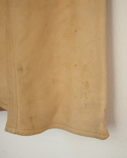 A close-up of a tan suede or leather fabric panel with visible stains and a stitched hem, shown against a plain off-white background.