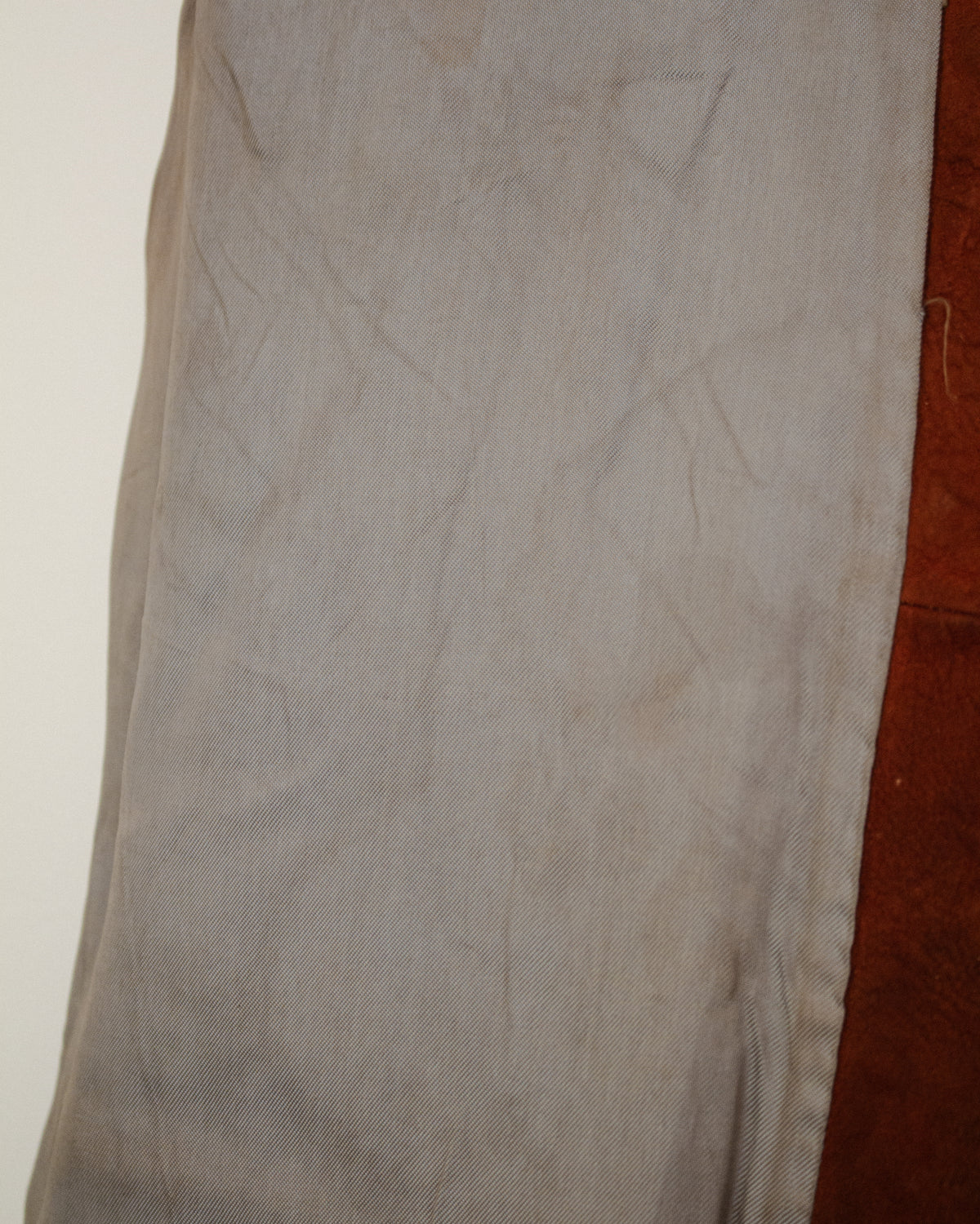 A close-up of a light gray fabric garment, showing the texture and folds.