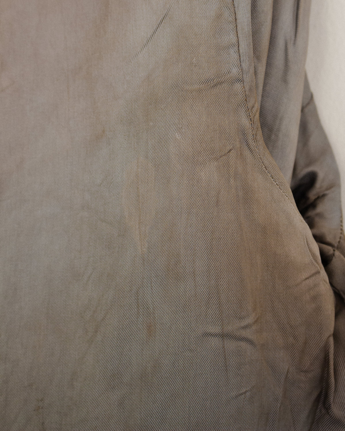 A close-up of a taupe-brown textured fabric, showing fine grain and subtle creases.