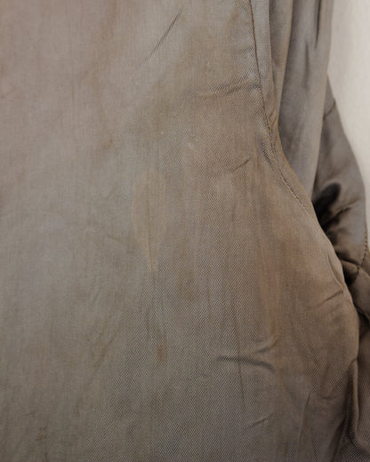 A close-up of a taupe-brown textured fabric, showing fine grain and subtle creases.