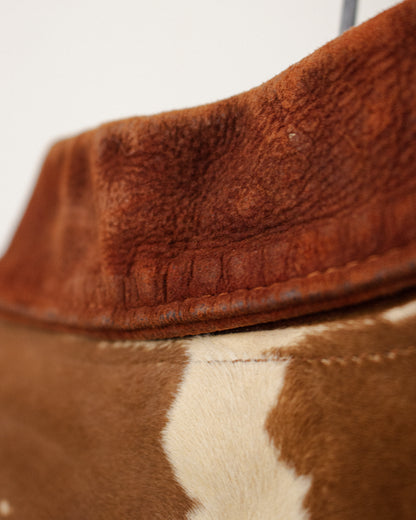 Close-up detail of a brown suede collar with a brown and white cowhide body, showing the texture and stitching.