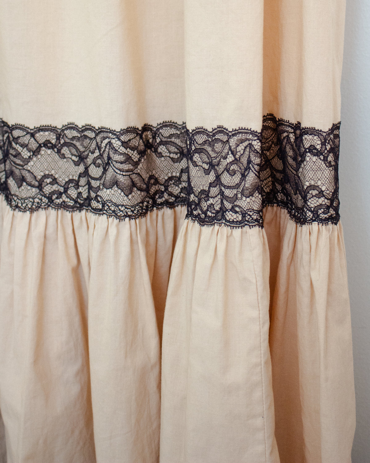 Close-up of a cream-colored fabric panel with a wide black lace band across the middle.
