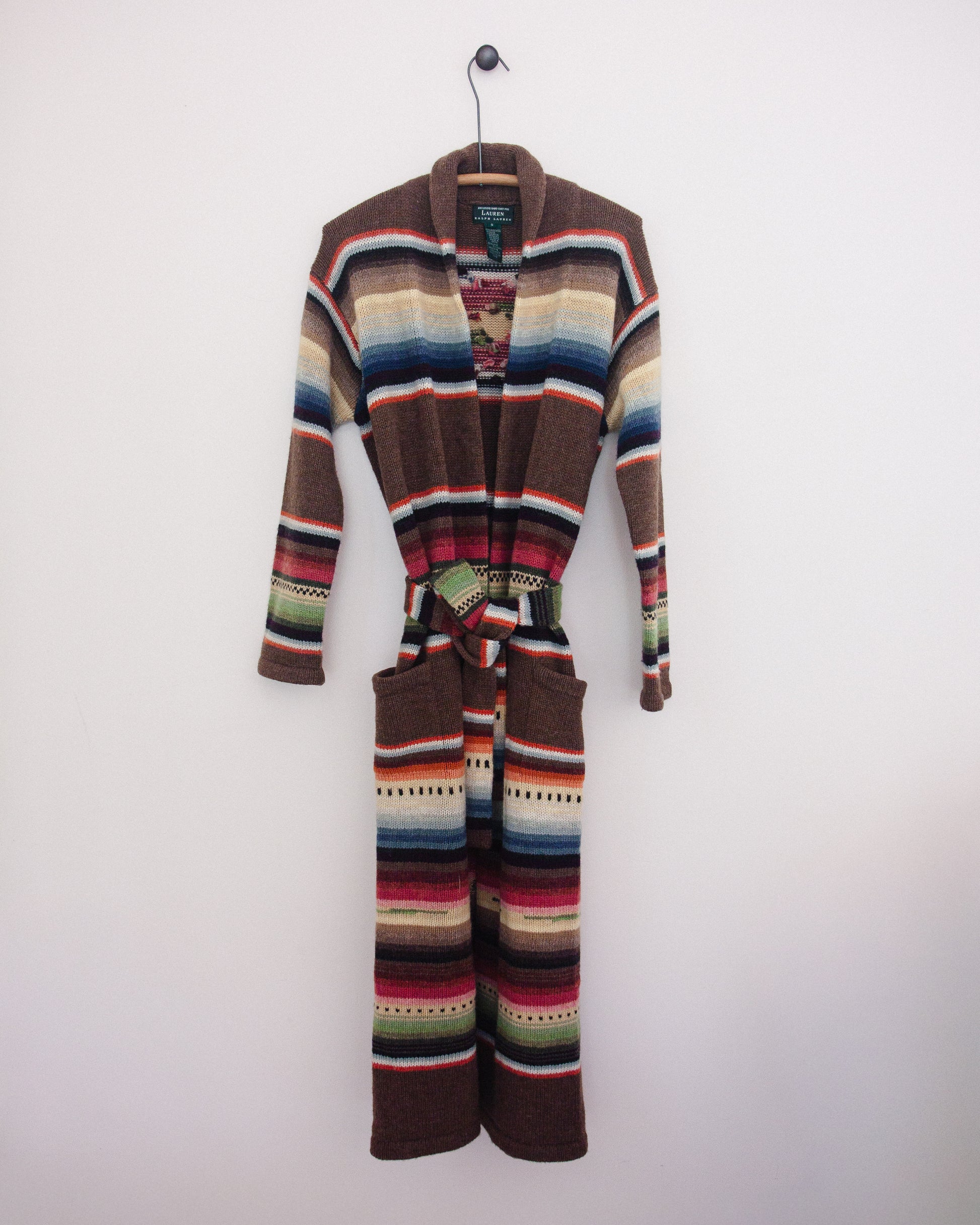 Multi colored cardigan with belt on hanger. 