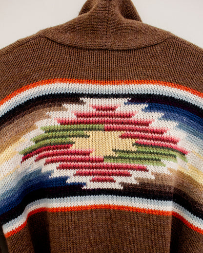 Close-up of a brown knit sweater featuring a Southwestern geometric pattern with red, green, blue, white, and orange stripes.
