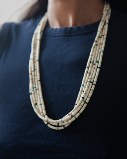 Woman wearing vintage 5-Strand Santo Domingo Heishi necklace on top of a navy shirt.