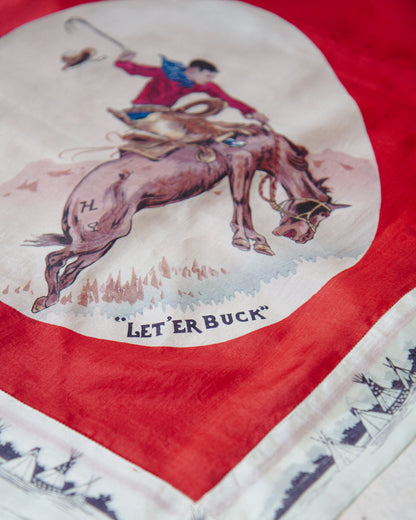 A close-up of a vintage western-themed scarf featuring a cowboy riding a bucking horse, with the text "LET'ER BUCK" printed below the illustration. The scarf has a bold red border and a white lower section with dark blue ship illustrations.
