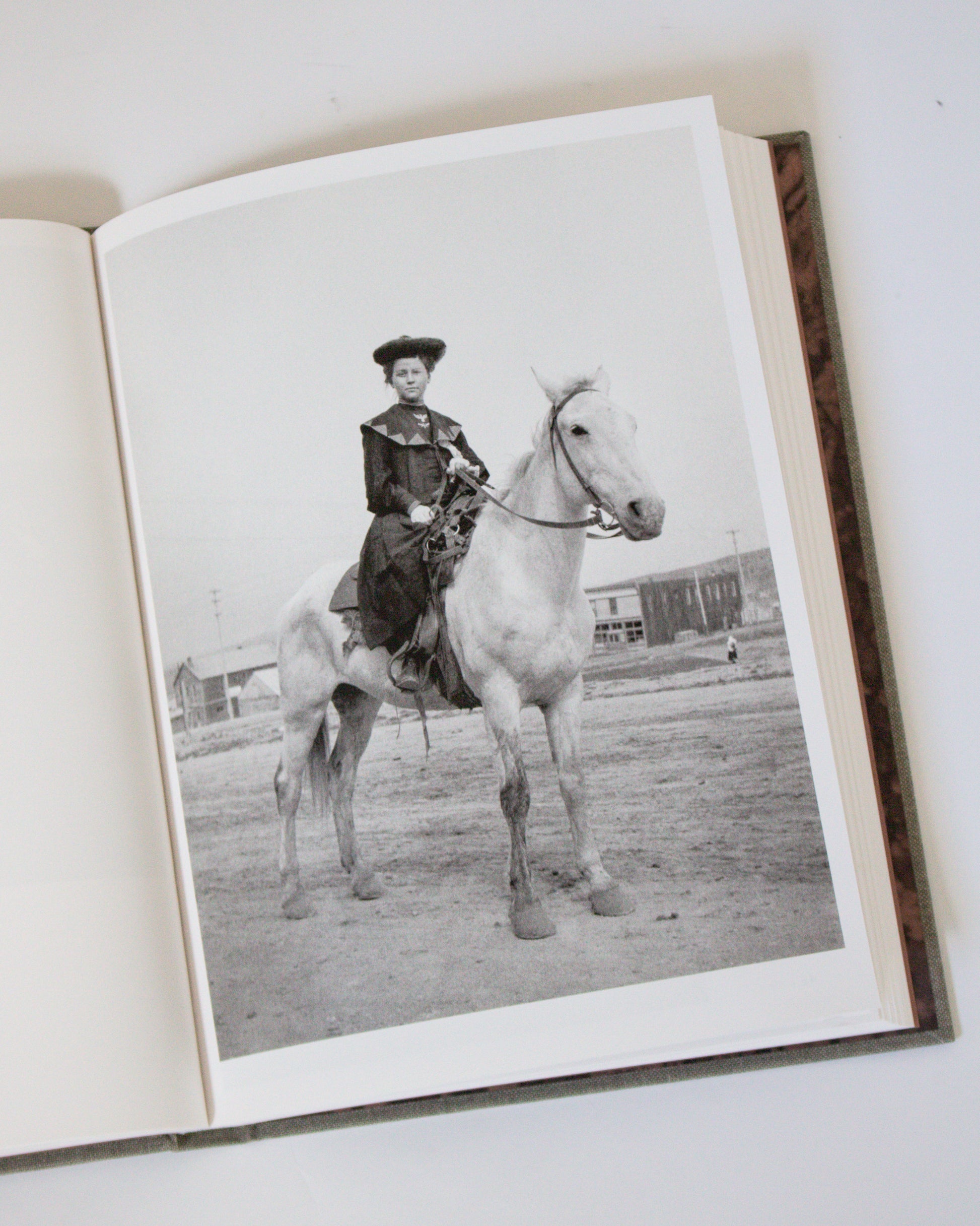 Open book with a black and white photograph of a person on a horse.
